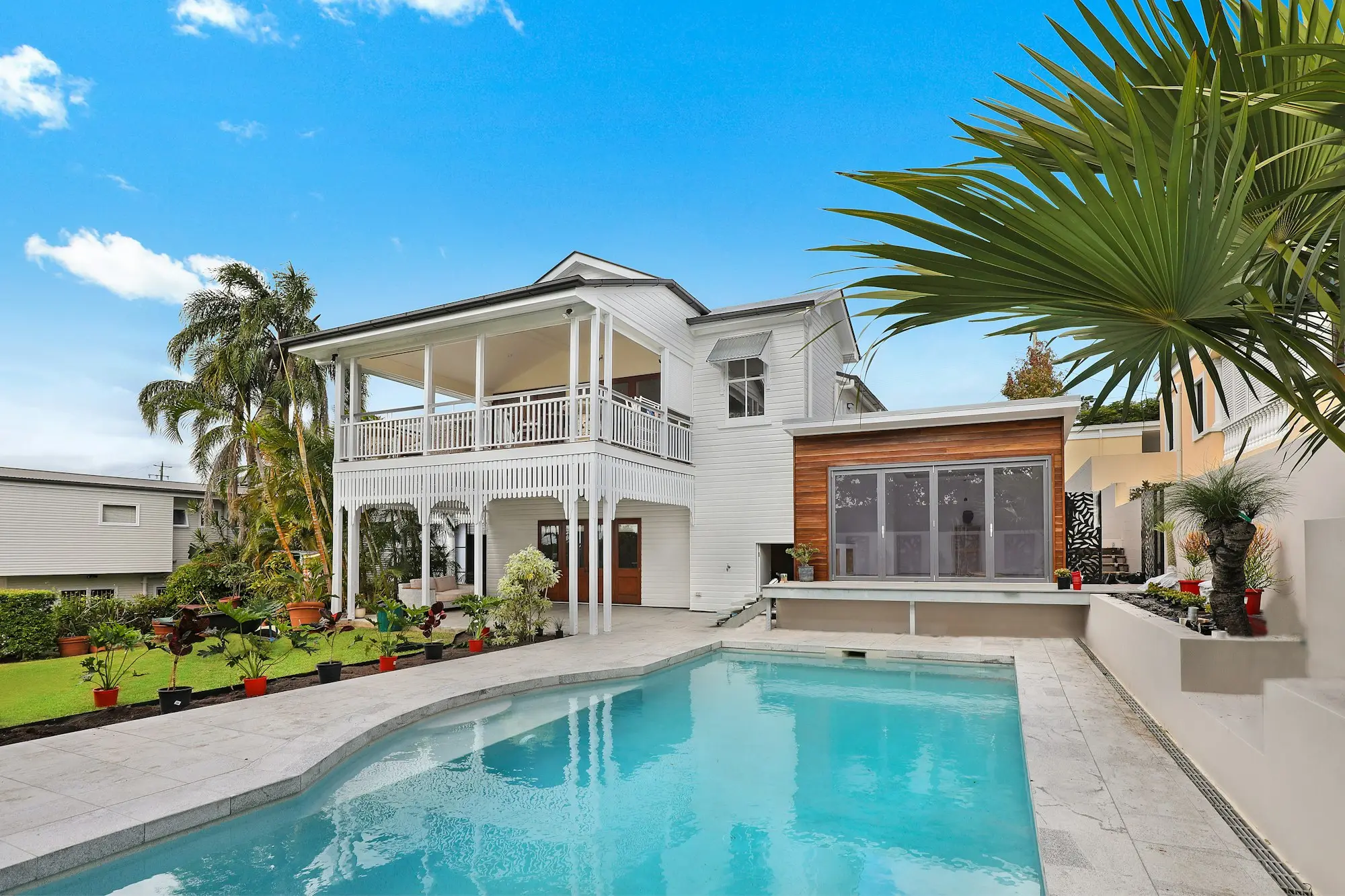 White house with a timber extension and a swimming pool in the garden