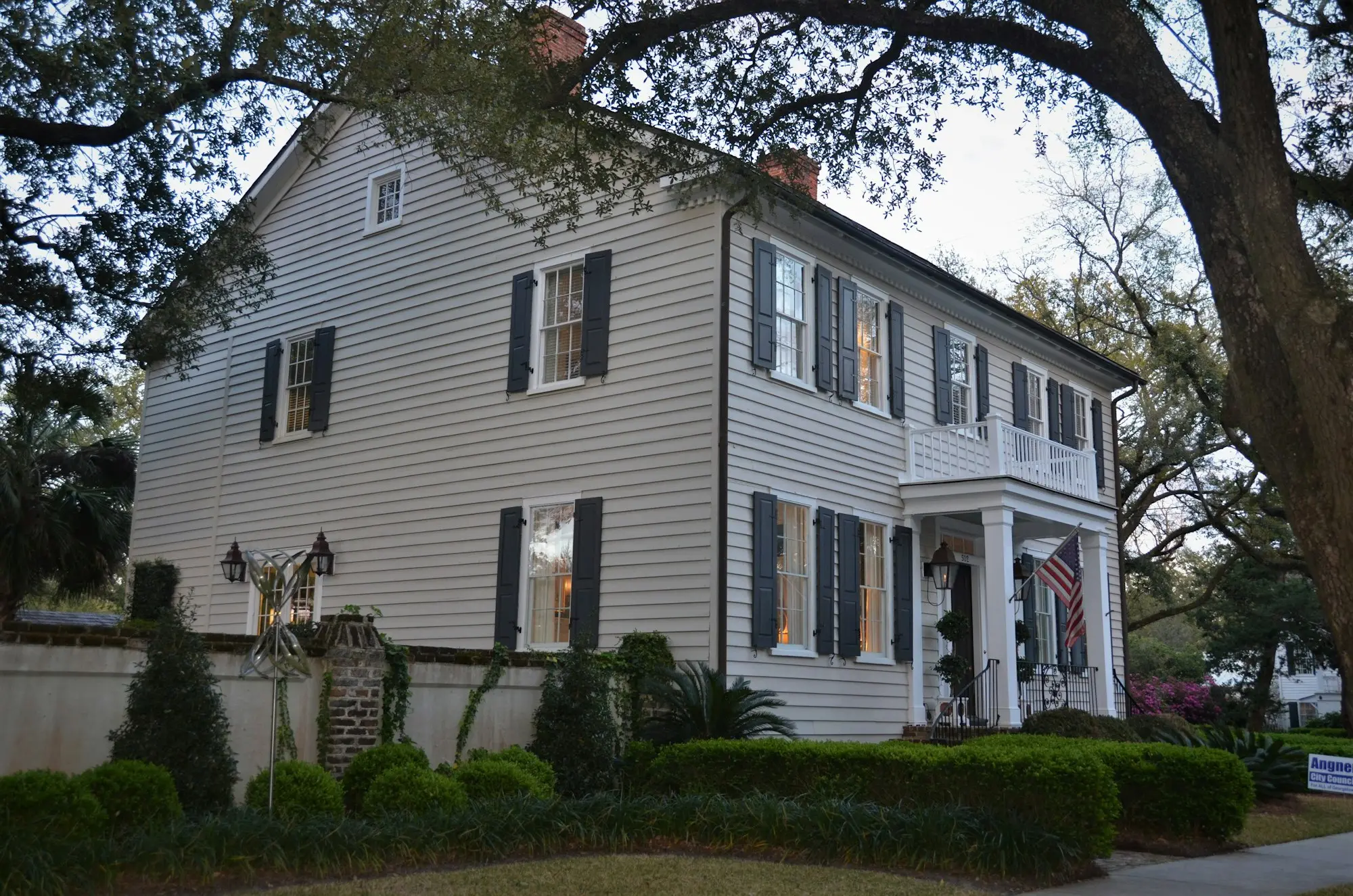 White timber house with dark trim surrounded by green trees